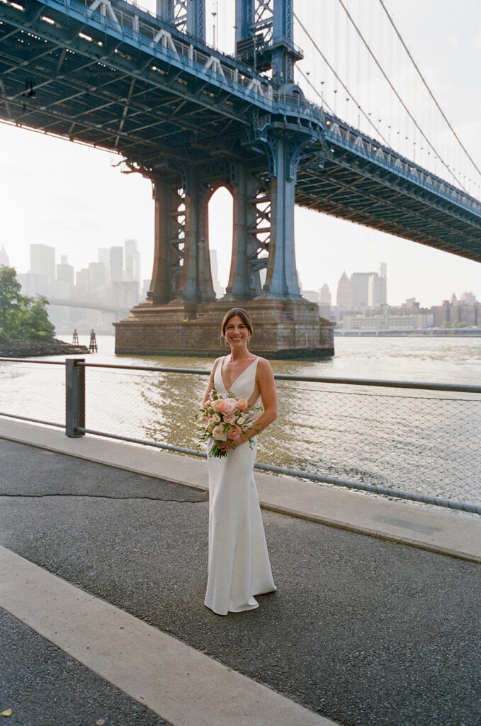 bride holding bouquet standing in front of brooklyn bridge to show Celestine Wedding brooklyn