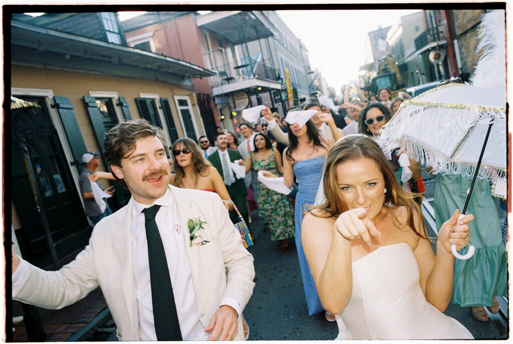 Bride and groom dancing and smiling at their second line around the block with ​hotels near brennan's new orleans in the back