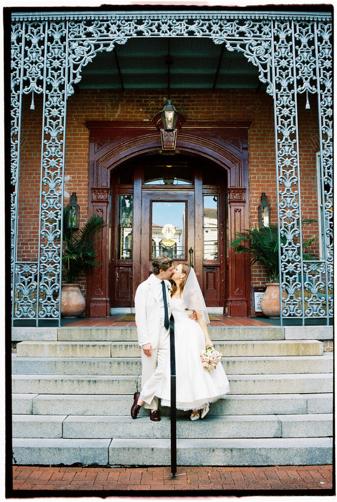 new orleans wedding pictures with bride and groom kissing in front of a hotel